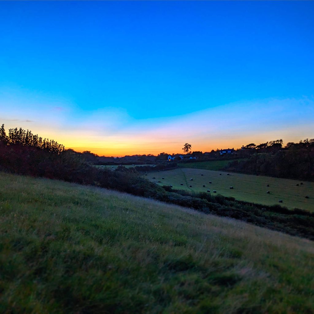 Sunset across fields with hay bails